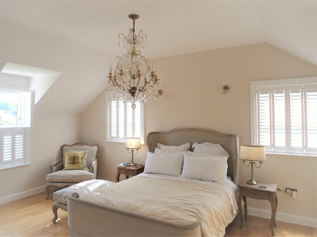 Bedroom with three windows, each with white closed shutters