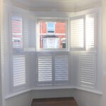 indoor view of white lounge shutters with one open door