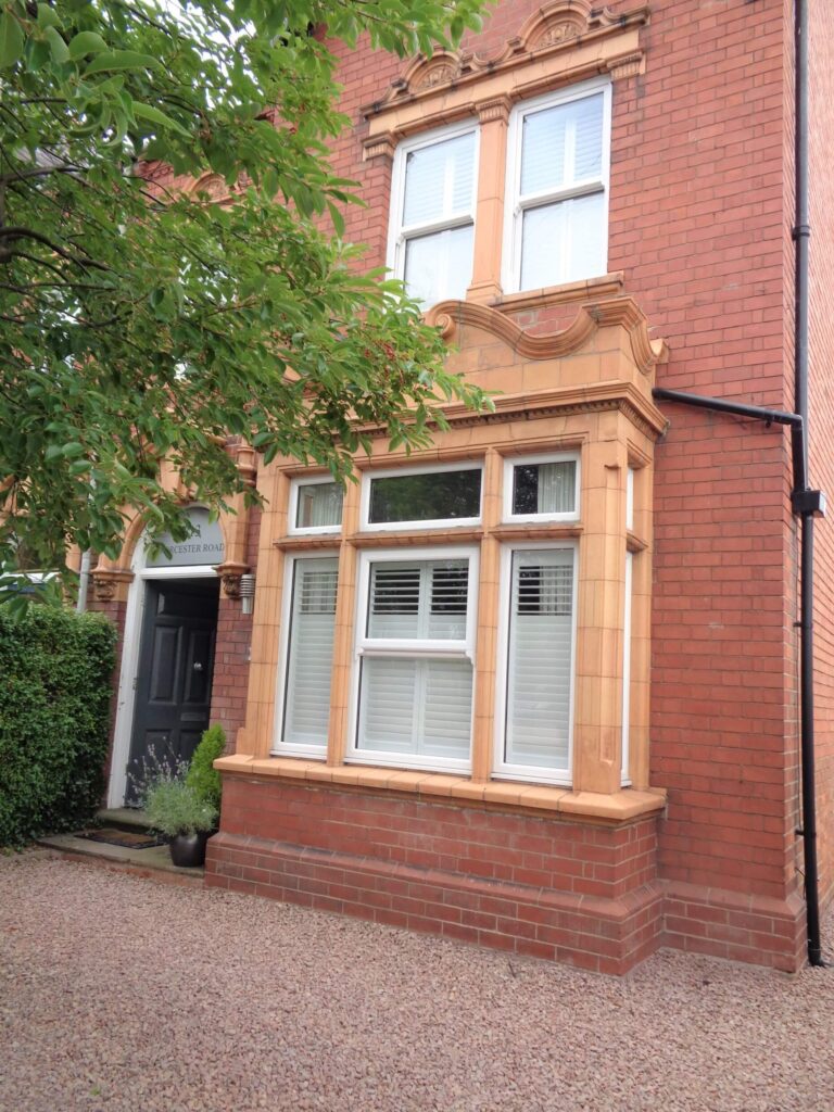 outside view of a box bay window in a Victorian home with white indoor shutters