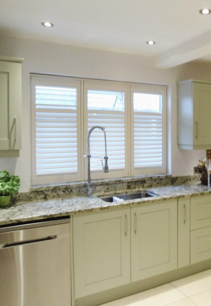 Sage green kitchen with white shutters